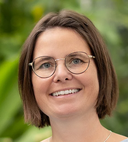 Nicole Dorn Rapunzel Mitarbeiterin steht vor blühender Pflanze.