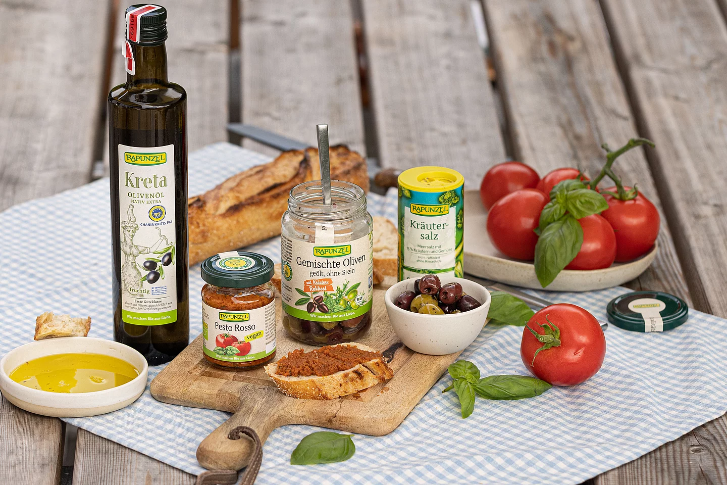 Mediterrane Antipasti mit Oliven, Pesto und Kreta-Olivenöl Stimmungsvolles Antipasti-Arrangement mit gemischten Oliven, Pesto Rosso und einer Flasche Kreta-Olivenöl, dekorativ angerichtet auf einem Tisch