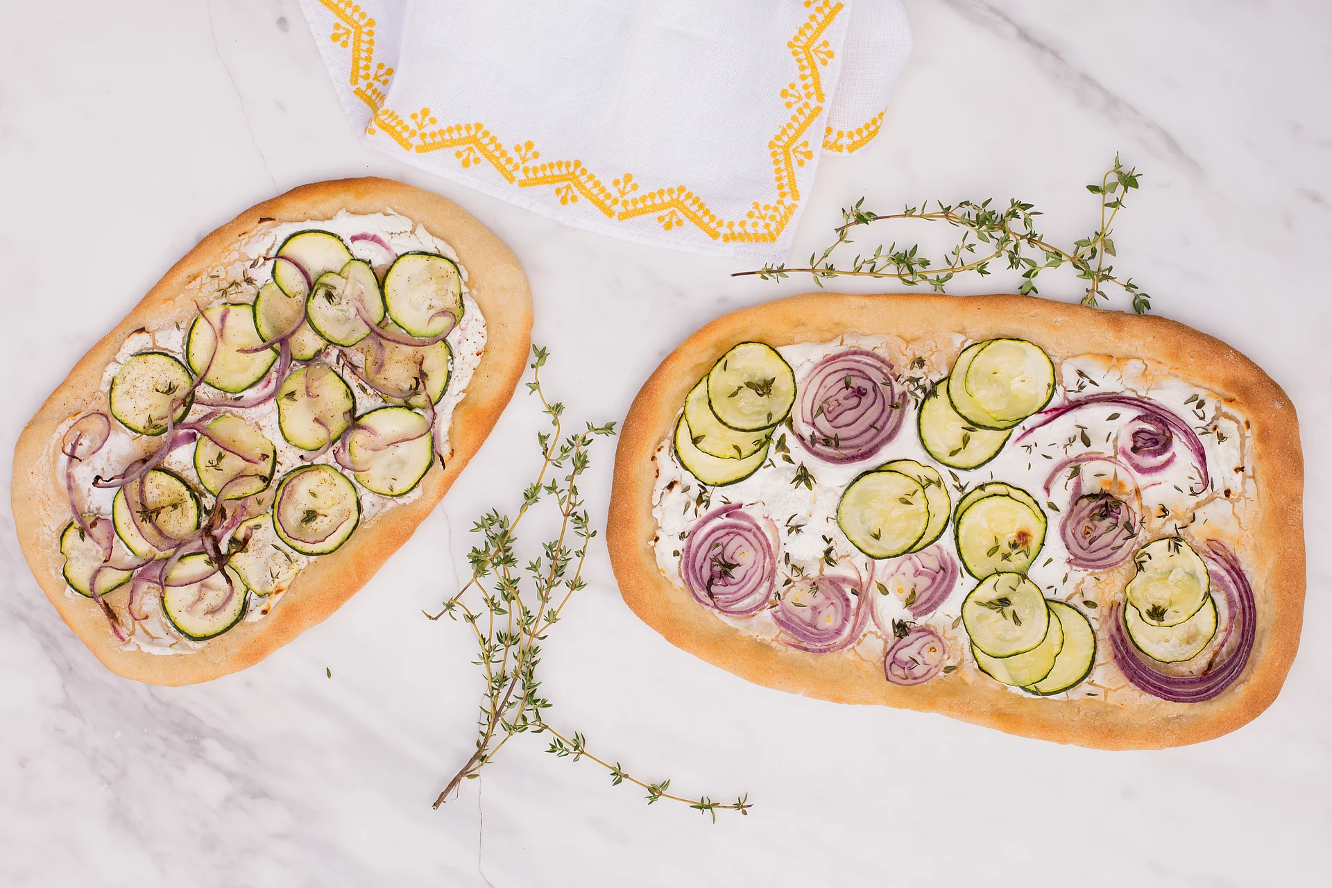 Zwei Pizzen mit Ziegenkäse, Zucchini und Lupinenmehl von oben fotografiert