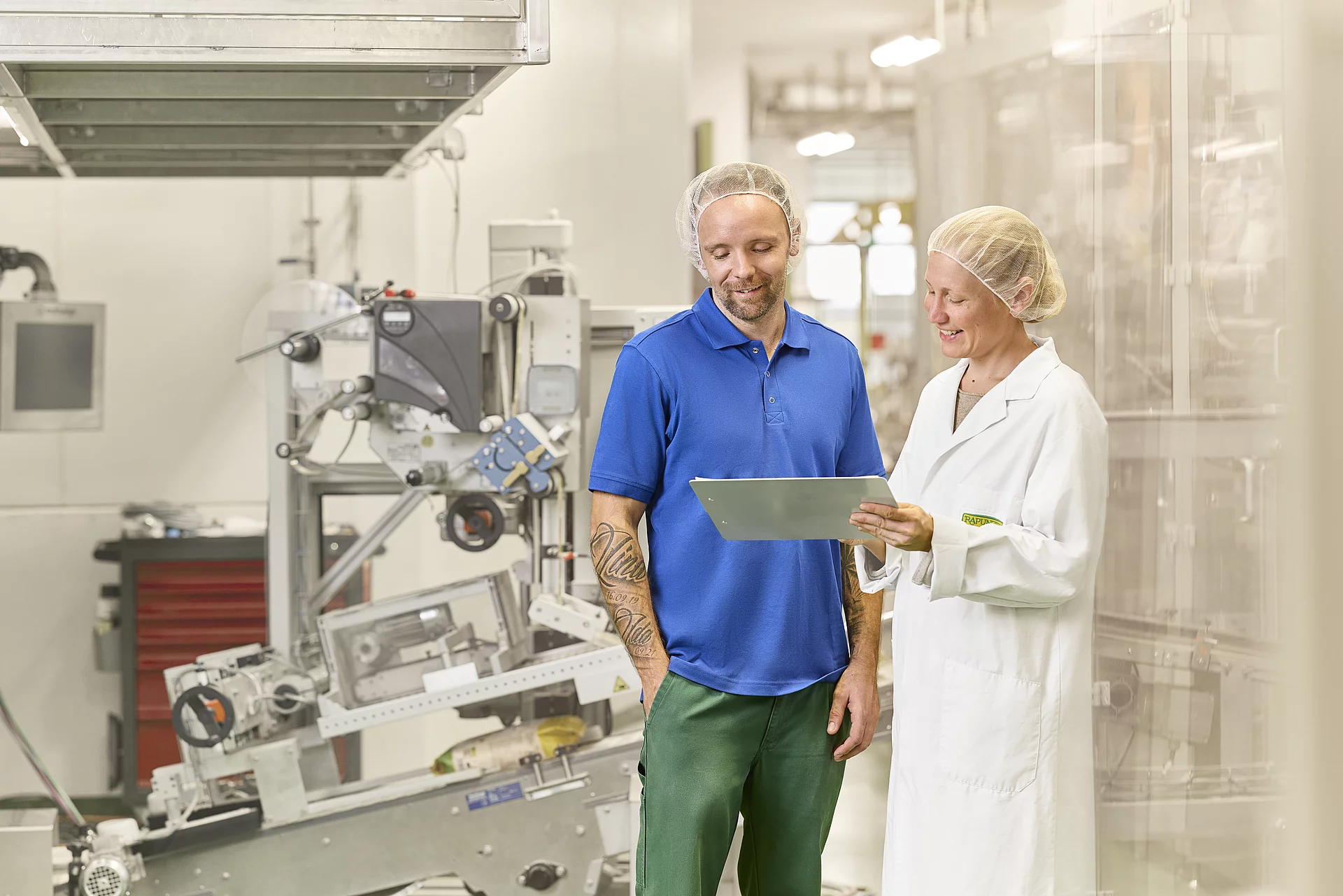 Die Qualitätssicherung nimmt alles genau unter die Lupe. Mitarbeiterin von der Qualitätssicherung bespricht sich mit dem Maschinenführer der Produktionsanlage für das Müsli.