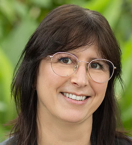 Simone Fischer Rapunzel Mitarbeiterin steht vor blühender Pflanze.