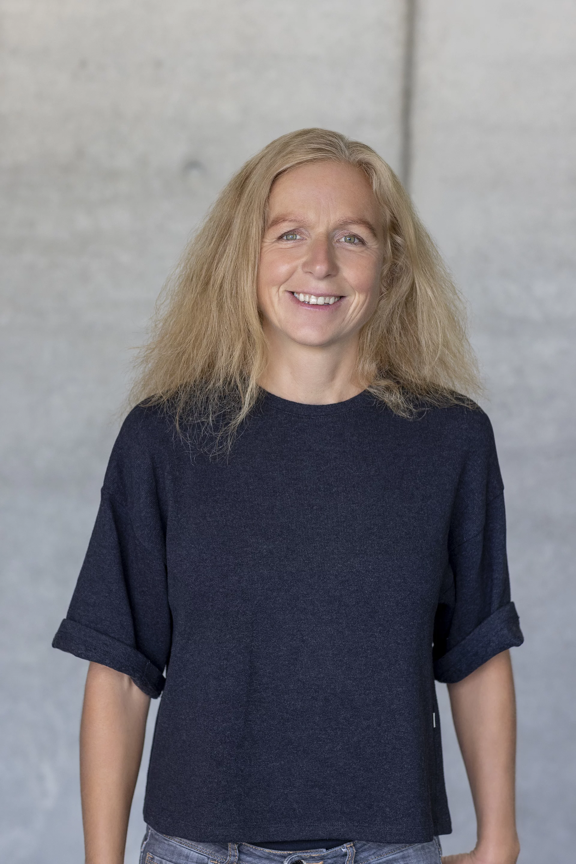 Porträt von Meike Bauer, Gesellschafterin, frontal aufgenommen und lächelnd vor unscharfem Hintergrund.