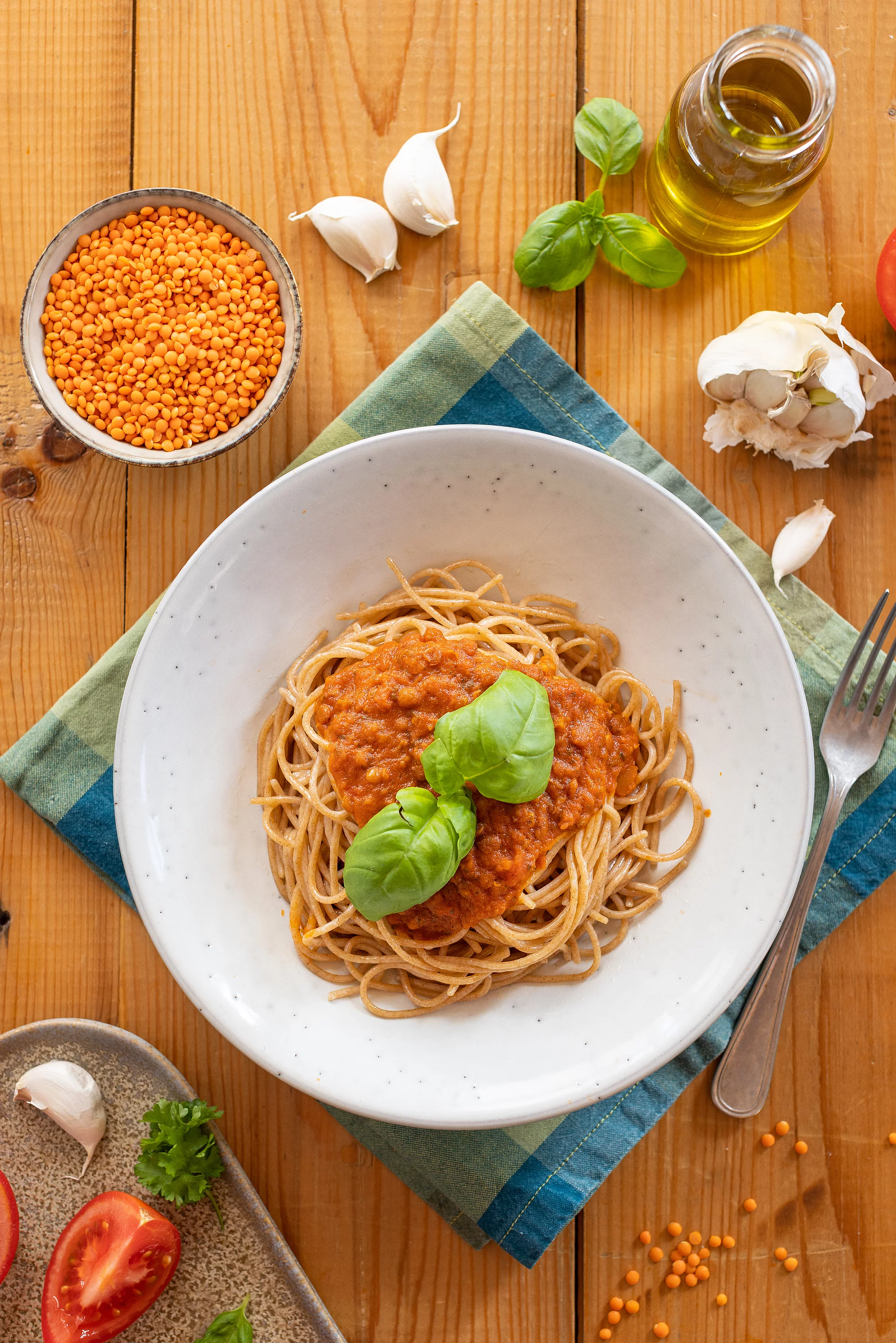 Rapunzel Linsenbolognese auf Spaghetti Ein weißr Teller mit Spaghetti und Linsenbolognese auf einem rustikalen Holztisch mit Kräutern
